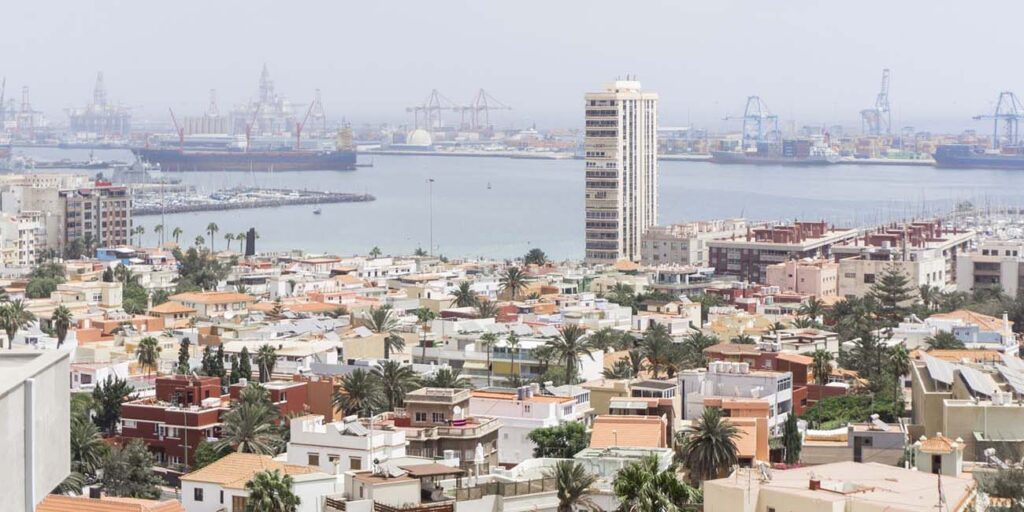 Hazy city view with a sea port and a cargo ship in the distance