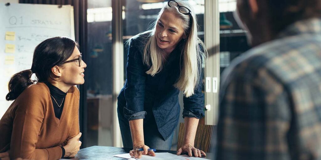 Senior business woman explaining business matters to her team in a boardroom. Mature manager planning new strategy with colleagues in meeting.