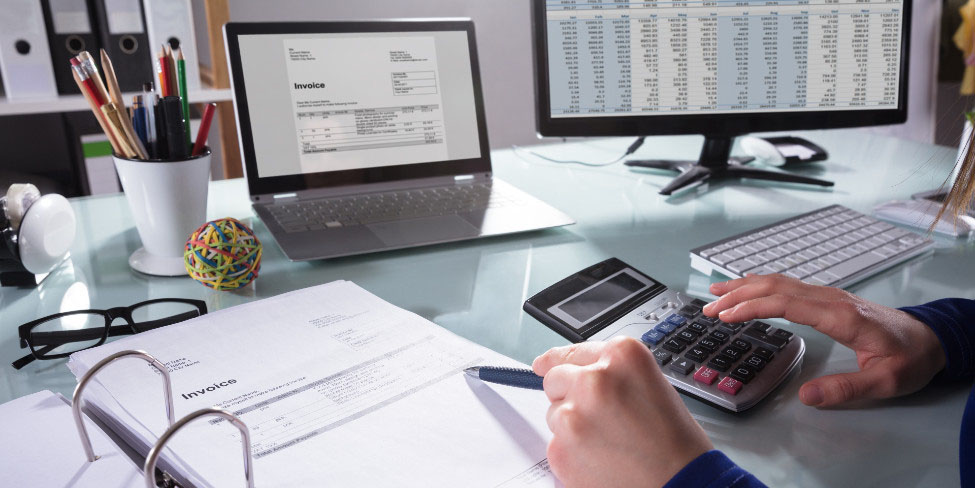 Person working at desk with calculators and laptops